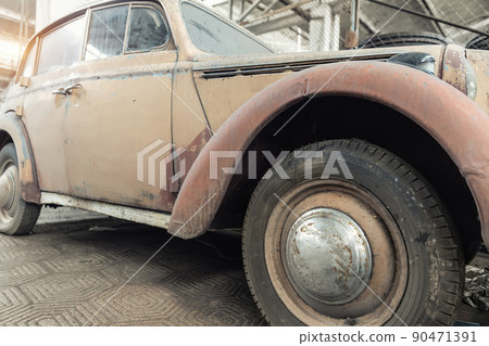 Side rusty abandoned forgotten antique oldtimer old car and motorcycles at junkyard factory storage warehouse indoors. Classic vintage retro vehicles detail garage workshop restore renovation station 90471391