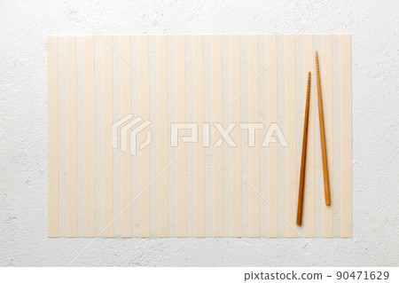 Two chopsticks and bamboo mat on cement background. Top view, copy space 90471629
