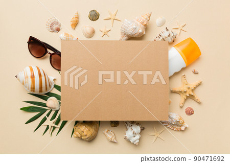 Summer time concept with blank greeting card and blank craft paper on colored background. Seashells from ocean shore in the shape of frame separated with space for text top view 90471692