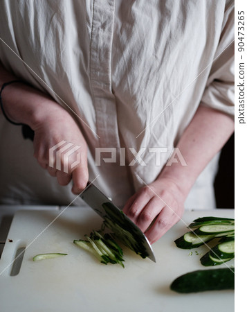 A person who cuts cucumbers 90473265