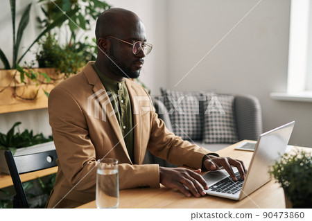 Serious young black man in formalwear consulting online patients in office 90473860