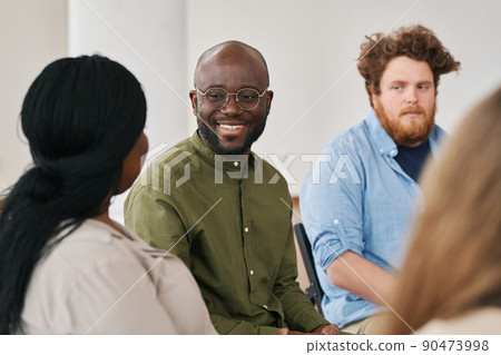 Happy young black man looking at one of patients during psychological session 90473998