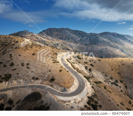 Aerial view of winding mountain road, blue sky at sunrise 90474007