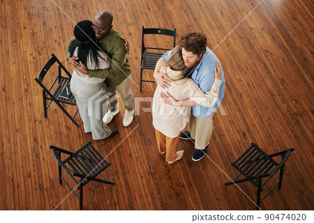 Two young interracial couples standing in embrace while comforting each other 90474020