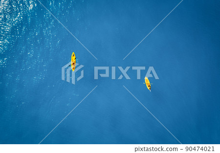 Aerial view of yellow kayaks in blue sea at sunset in summer 90474021