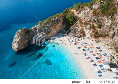 Aerial view of blue sea, rock, sandy beach with umbrellas Aerial view of blue sea, rock, sandy beach with umbrellas 90474038
