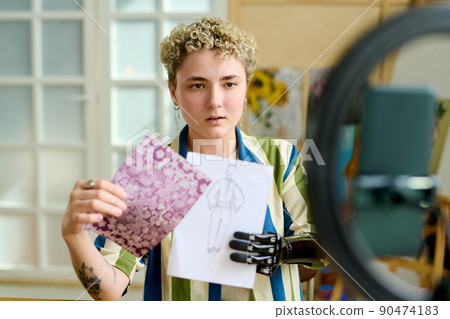 Young creative female fashion designer showing drawing to online audience Young creative female fashion designer showing drawing to online audience 90474183