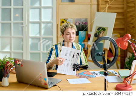 Young female fashion designer with arm prosthesis showing sketch of new models Young female fashion designer with arm prosthesis showing sketch of new models 90474184