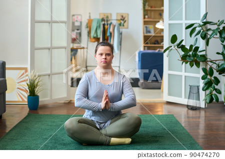 Young woman with disability sitting in pose of lotus while practicing yoga Young woman with disability sitting in pose of lotus while practicing yoga 90474270