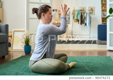 Young female in activewear keeping hands put together in front of her face 90474272