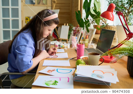 Young female with Down syndrome drawing letters with crayons on paper 90474308