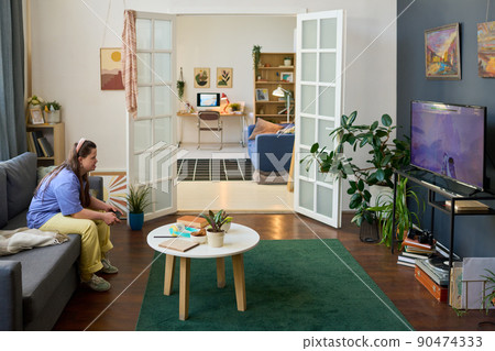 Young female with Down syndrome playing video game in front of tv screen Young female with Down syndrome playing video game in front of tv screen 90474333