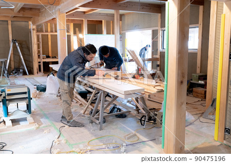 Carpenter working at the construction site of a wooden house 90475196