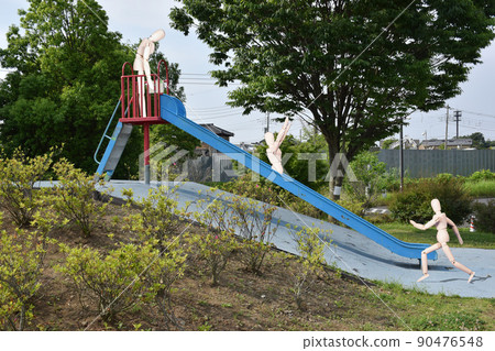 Three mannequins are playing on the slide. One person is waiting. Another raises his hand and cheers. Others are running. 90476548