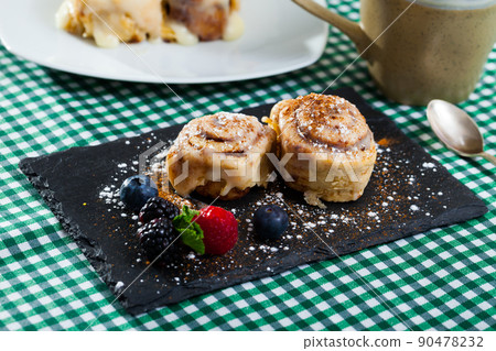 Tasty baked cinnabon rolls served with powdered sugar and berries 90478232