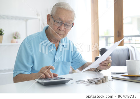 Serious man sitting at table near utility bill and calculating expenses Serious man sitting at table near utility bill and calculating expenses 90479735