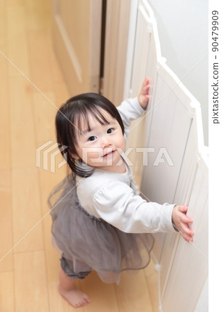 一個 1 歲的女孩抱著嬰兒圍欄玩耍 90479909