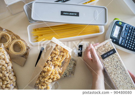 Closeup female hands applying printing sticker with oat flakes title on transparent plastic case 90480080