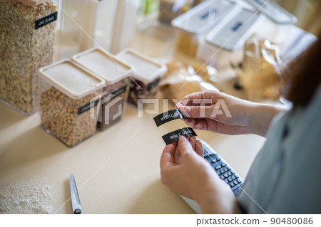 Top view female hands creating names title stickers for food comfortable storage use labeler machine 90480086