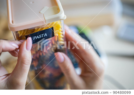 Closeup female hands sticking label on plastic package pasta. Storage organization of food products 90480099