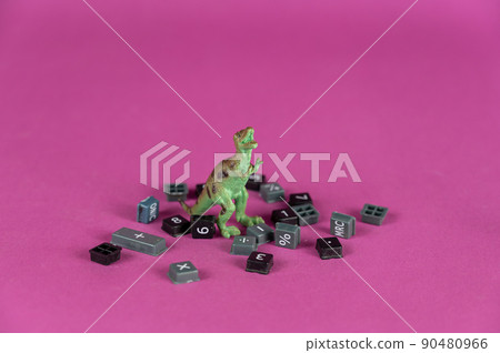A miniature dinosaur against a purple background. Small black arithmetic calculator buttons scattered around. Green figure of a predatory animal standing on its hind legs. Selective focus. A miniature dinosaur against a purple background. Small black arithmetic calculator buttons scattered around. Green figure of a predatory animal standing on its hind legs. Selective focus. 90480966