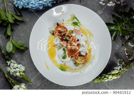 An ideal breakfast. Cottage cheese pancakes with caramel, almonds and cream sauce in a white plate. Ukrainian syrniki An ideal breakfast. Cottage cheese pancakes with caramel, almonds and cream sauce in a white plate. Ukrainian syrniki 90481912