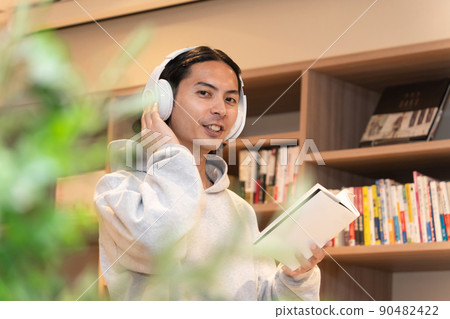 Men in headphones reading a book Men in headphones reading a book 90482422