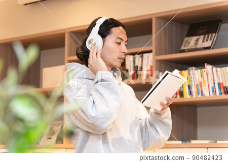 Men in headphones reading a book Men in headphones reading a book 90482423