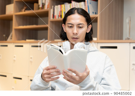 Men in headphones reading a book Men in headphones reading a book 90485002