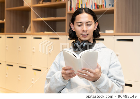 Men in headphones reading a book Men in headphones reading a book 90485149