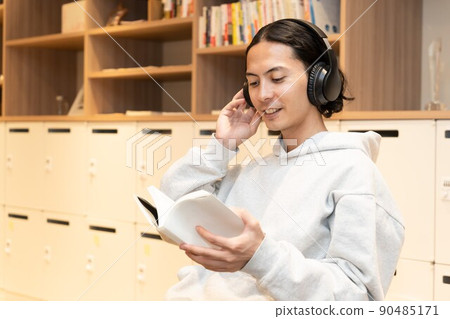 Men in headphones reading a book Men in headphones reading a book 90485171