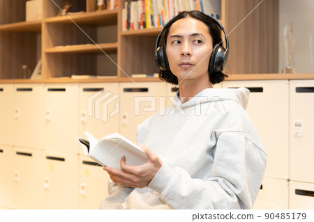 Men in headphones reading a book Men in headphones reading a book 90485179