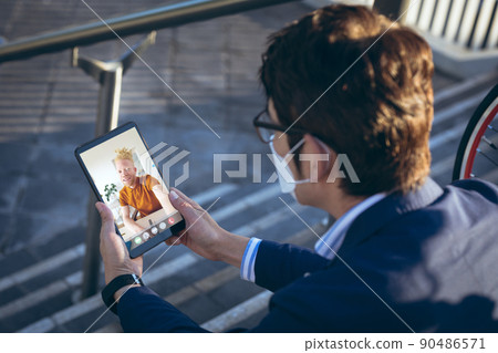 Asian businessman wearing mask during video call with albino african american male colleague Asian businessman wearing mask during video call with albino african american male colleague 90486571