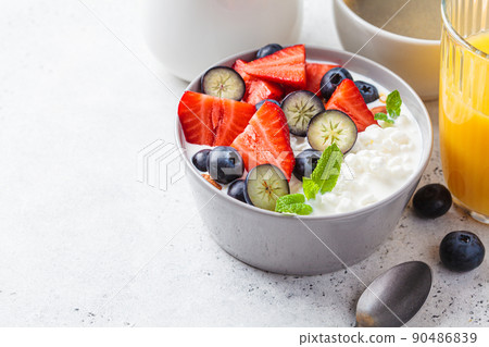Cottage cheese with strawberries, nuts and blueberries in gray bowl for breakfast. Summer recipe. Cottage cheese with strawberries, nuts and blueberries in gray bowl for breakfast. Summer recipe. 90486839