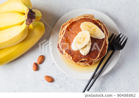 Banana pancakes with syrup on white plate, gray background. Vegan recipe concept. Banana pancakes with syrup on white plate, gray background. Vegan recipe concept. 90486862