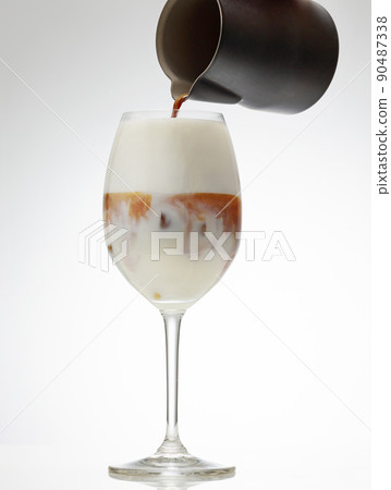 coffee espresso pouring into glass of iced milk 90487338