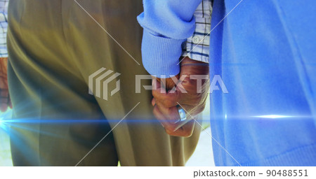 Image of light moving over midsection of senior couple walking holding hands 90488551