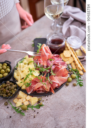 Woman holding piece of prosciutto ham on a fork standing at domestic kitchen Woman holding piece of prosciutto ham on a fork standing at domestic kitchen 90488784