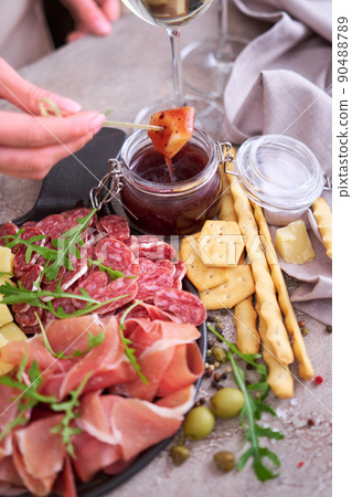 woman dips parmesan cheese into sauce, Two glasses of white wine and Italian antipasto meat platter woman dips parmesan cheese into sauce, Two glasses of white wine and Italian antipasto meat platter 90488789