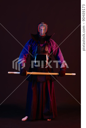 Close up shot, Kendo fighter wearing in an armor, traditional kimono, helmet practicing martial art with shinai bamboo sword, black background. Close up shot, Kendo fighter wearing in an armor, traditional kimono, helmet practicing martial art with shinai bamboo sword, black background. 90489173