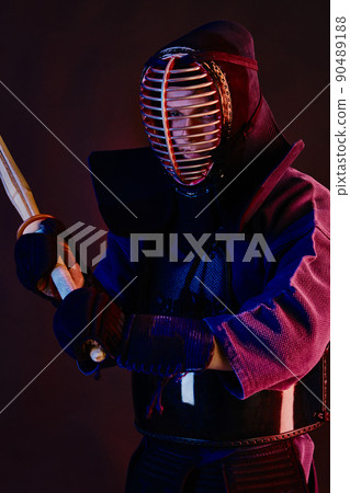 Close up shot, Kendo fighter wearing in an armor, traditional kimono, helmet practicing martial art with shinai bamboo sword, black background. Close up shot, Kendo fighter wearing in an armor, traditional kimono, helmet practicing martial art with shinai bamboo sword, black background. 90489188