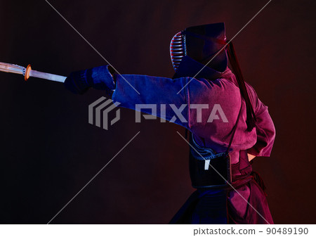 Close up shot, Kendo fighter wearing in an armor, traditional kimono, helmet practicing martial art with shinai bamboo sword, black background. Close up shot, Kendo fighter wearing in an armor, traditional kimono, helmet practicing martial art with shinai bamboo sword, black background. 90489190