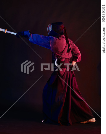 Close up shot, Kendo fighter wearing in an armor, traditional kimono, helmet practicing martial art with shinai bamboo sword, black background. Close up shot, Kendo fighter wearing in an armor, traditional kimono, helmet practicing martial art with shinai bamboo sword, black background. 90489191