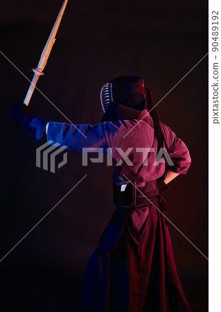 Close up shot, Kendo fighter wearing in an armor, traditional kimono, helmet practicing martial art with shinai bamboo sword, black background. Close up shot, Kendo fighter wearing in an armor, traditional kimono, helmet practicing martial art with shinai bamboo sword, black background. 90489192