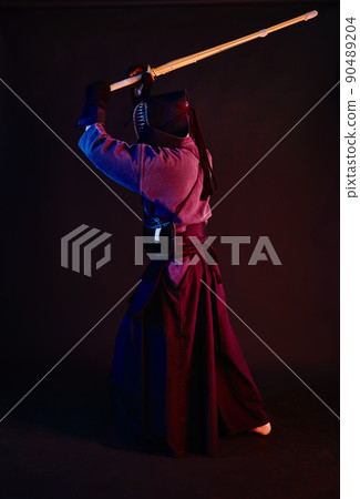 Close up shot, Kendo fighter wearing in an armor, traditional kimono, helmet practicing martial art with shinai bamboo sword, black background. Close up shot, Kendo fighter wearing in an armor, traditional kimono, helmet practicing martial art with shinai bamboo sword, black background. 90489204
