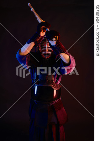 Close up shot, Kendo fighter wearing in an armor, traditional kimono, helmet practicing martial art with shinai bamboo sword, black background. Close up shot, Kendo fighter wearing in an armor, traditional kimono, helmet practicing martial art with shinai bamboo sword, black background. 90489205