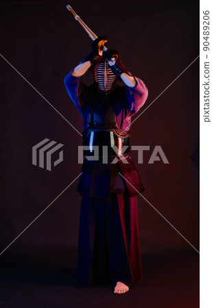 Close up shot, Kendo fighter wearing in an armor, traditional kimono, helmet practicing martial art with shinai bamboo sword, black background. Close up shot, Kendo fighter wearing in an armor, traditional kimono, helmet practicing martial art with shinai bamboo sword, black background. 90489206