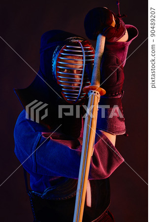 Close up shot, Kendo fighter wearing in an armor, traditional kimono, helmet practicing martial art with shinai bamboo sword, black background. Close up shot, Kendo fighter wearing in an armor, traditional kimono, helmet practicing martial art with shinai bamboo sword, black background. 90489207