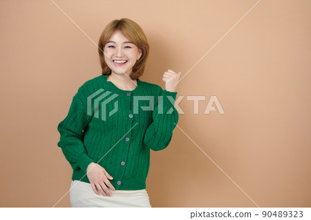 Photo of cute surprised woman pointing back thumb up empty space isolated on beige background Photo of cute surprised woman pointing back thumb up empty space isolated on beige background 90489323
