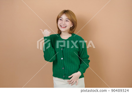 Young smiling happy nice beautiful asian woman pointing thumb finger back side on workspace area copy space on beige background Young smiling happy nice beautiful asian woman pointing thumb finger back side on workspace area copy space on beige background 90489324